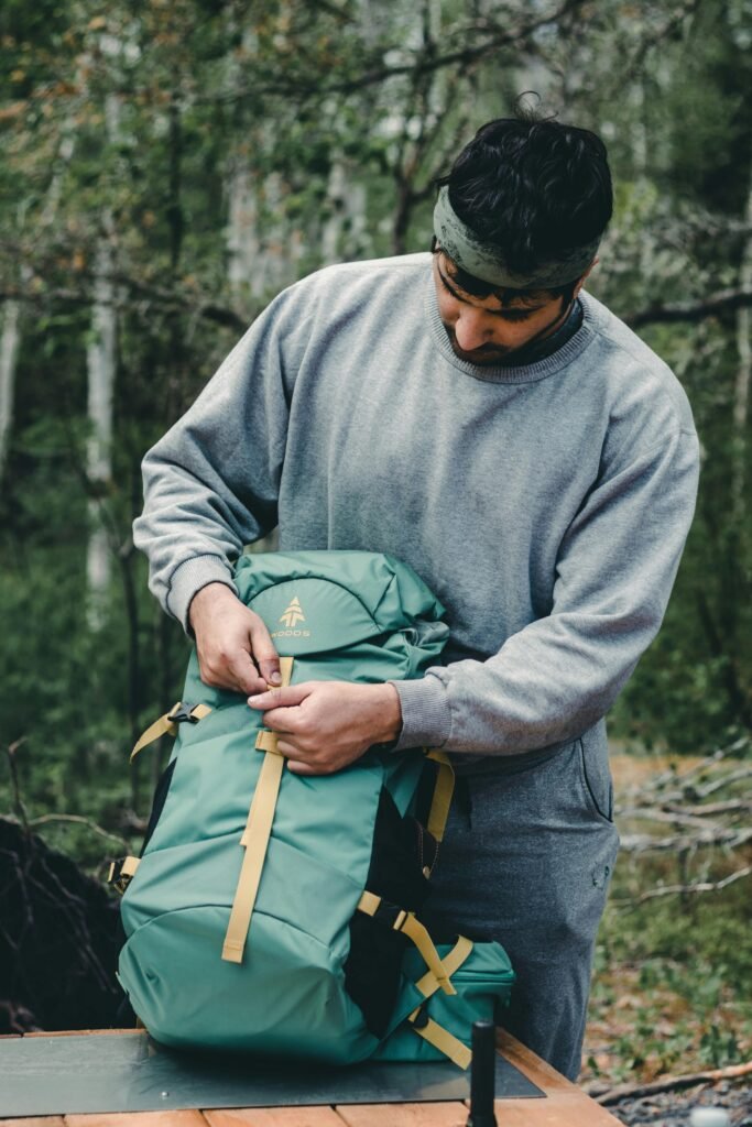 Man packing a budget bug out bag with affordable survival essentials for emergency preparedness.