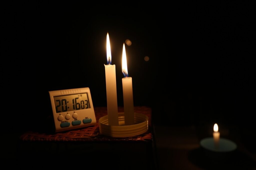 Candlelight during a power outage with two candles illuminating a dark room — symbolizing preparedness and calm survival planning.