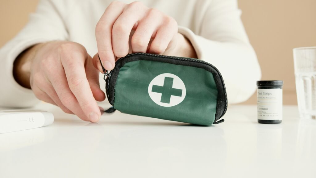 Person packing a small green first aid kit with medical and herbal supplies for backyard first aid and survival preparation.