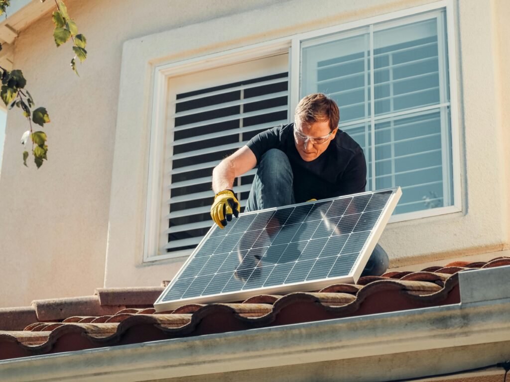 Person installing solar panels on a roof as part of a DIY solar power backup system for emergency preparedness