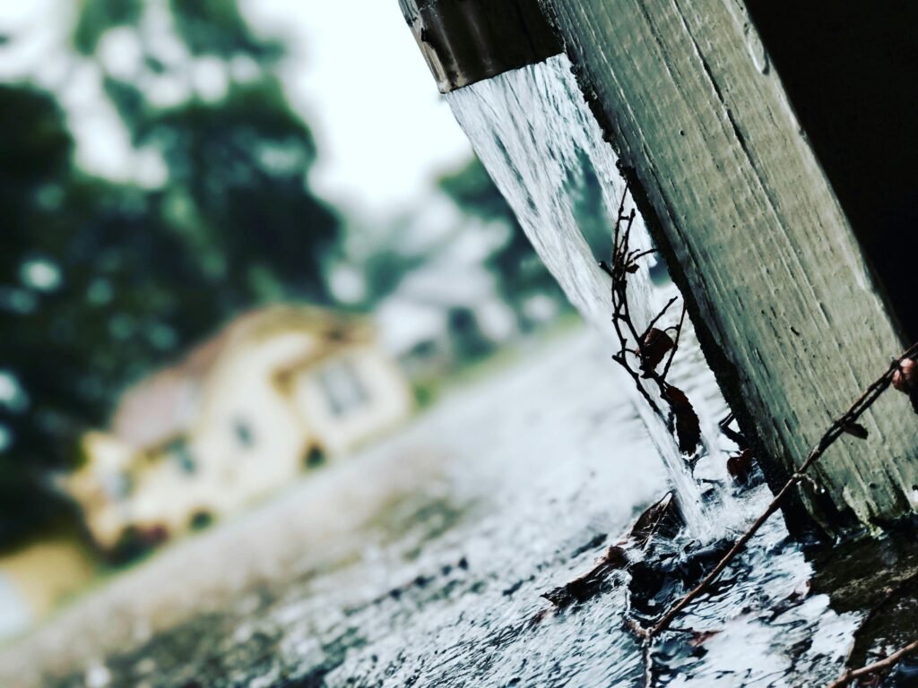 Rainwater collection system with gutter and barrel collecting rainwater in a backyard