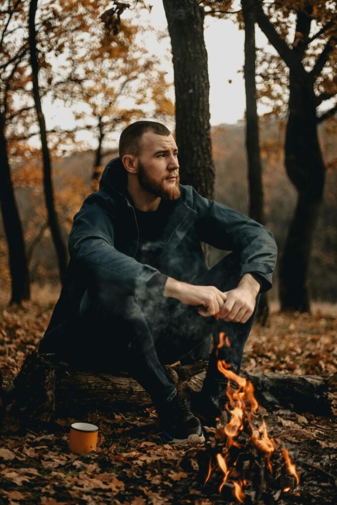 Man sitting by a campfire in the forest practicing the prepper mindset and mental preparedness.