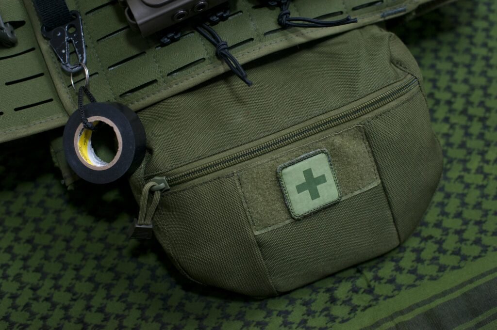 Olive green tactical first aid pouch on a textured surface, symbolizing emergency preparedness and urban survival prepping gear.