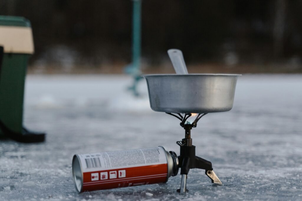 Portable camping stove and mug in snow, symbolizing winter emergencies and cold weather survival preparedness.