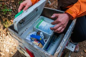 A 72 hour emergency kit inside a plastic tote containing water, hygiene supplies, gloves, snacks, and a flashlight laid out for disaster preparedness.